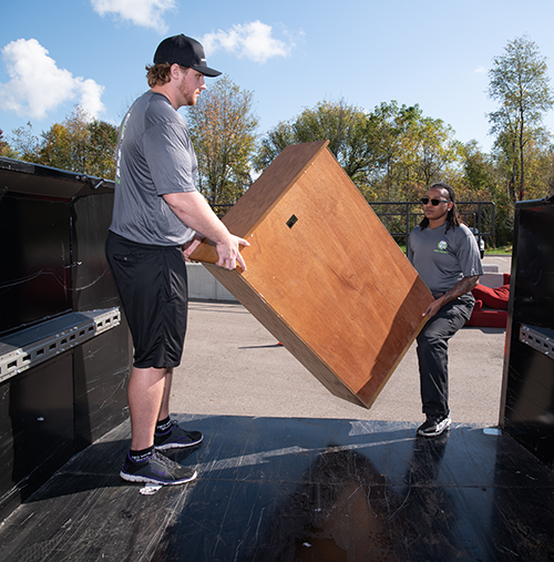 Junk removal specialists carrying a piece of furniture into a bin